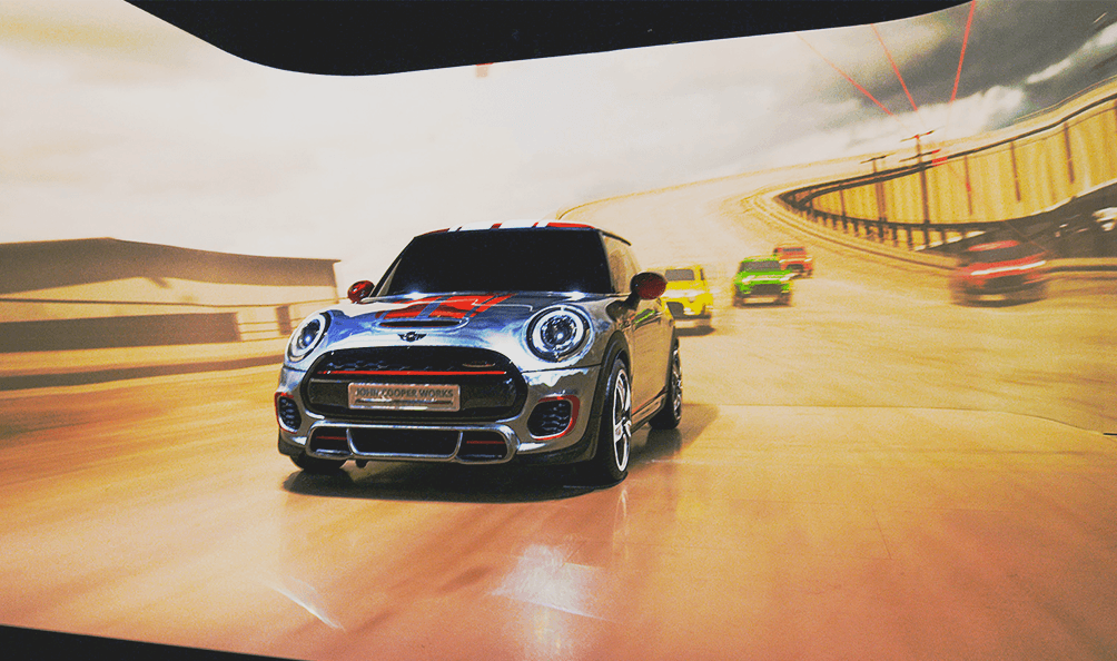 Mini stands in front of a projected highway